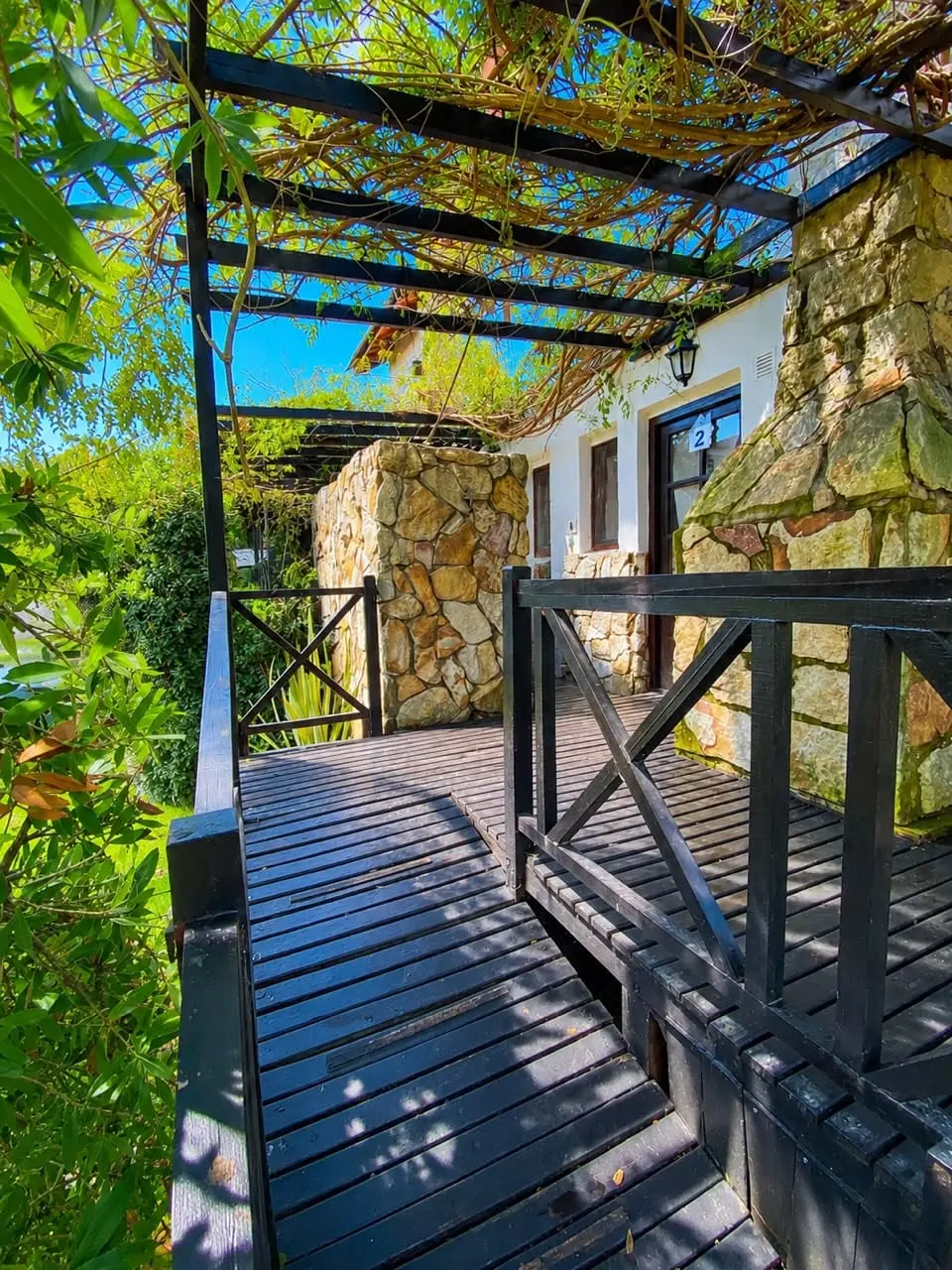 Deck de acceso al Refugio de Mar en Mar de las Pampas, con pérgola y muro de piedra
